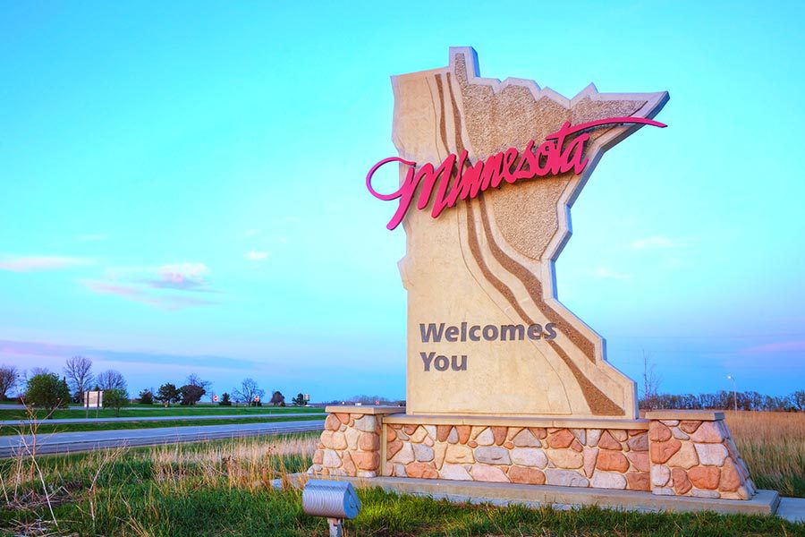 Hutchinson, MN Insurance - Large Sculpted Sign Reading ”Minnesota Welcomes You” Sitting along the Side of a Small Road